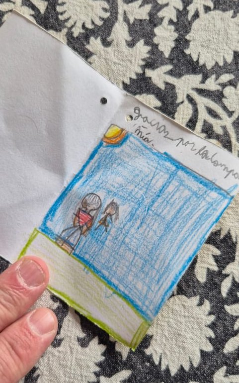 Interior de la tarjeta: un dibujo a lápiz de dos personas frente a un gran rectángulo azul, bajo un sol, con la dedicatoria «Gracias por la compañía».